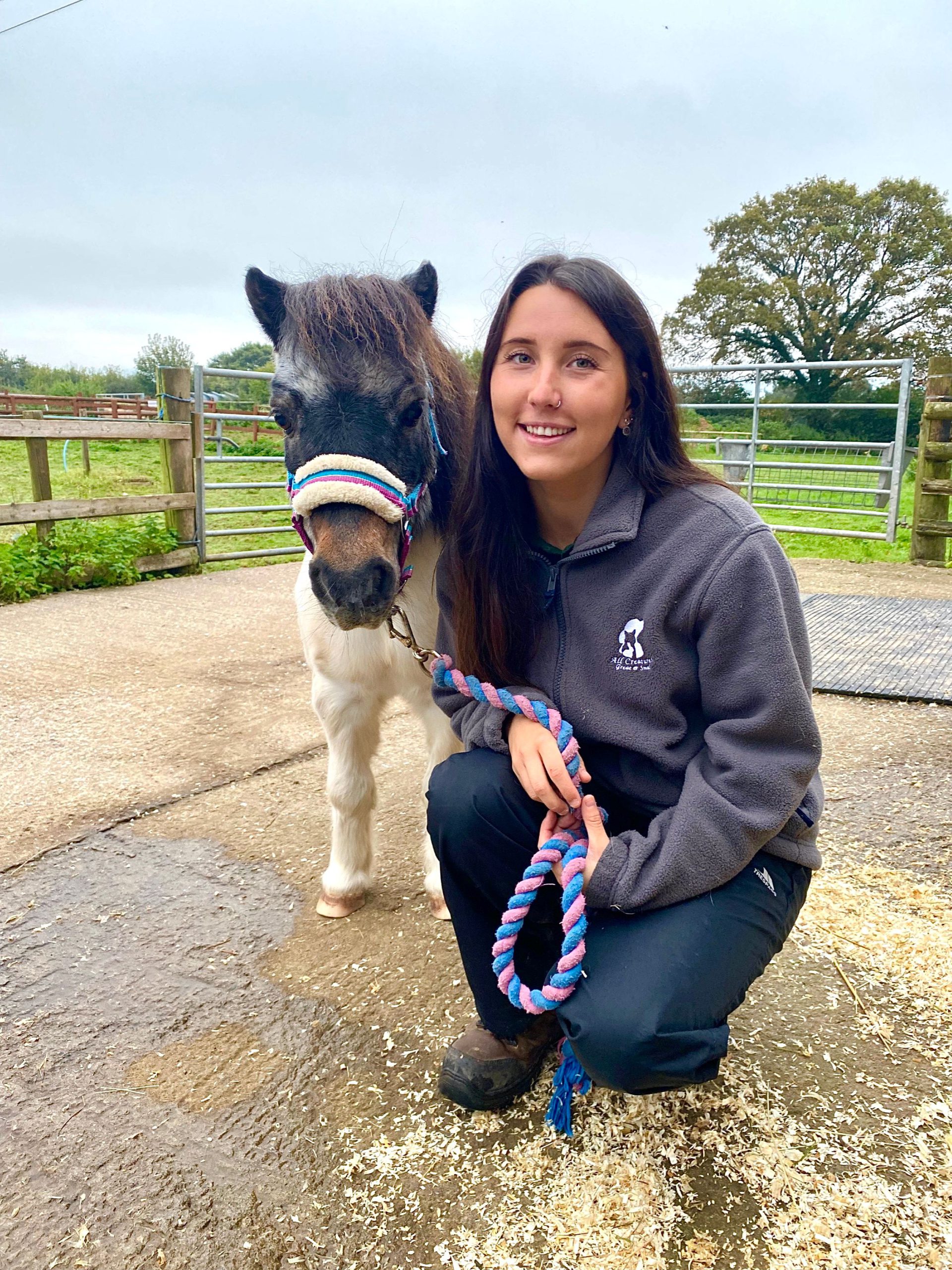 A person kneeled down next to a pony